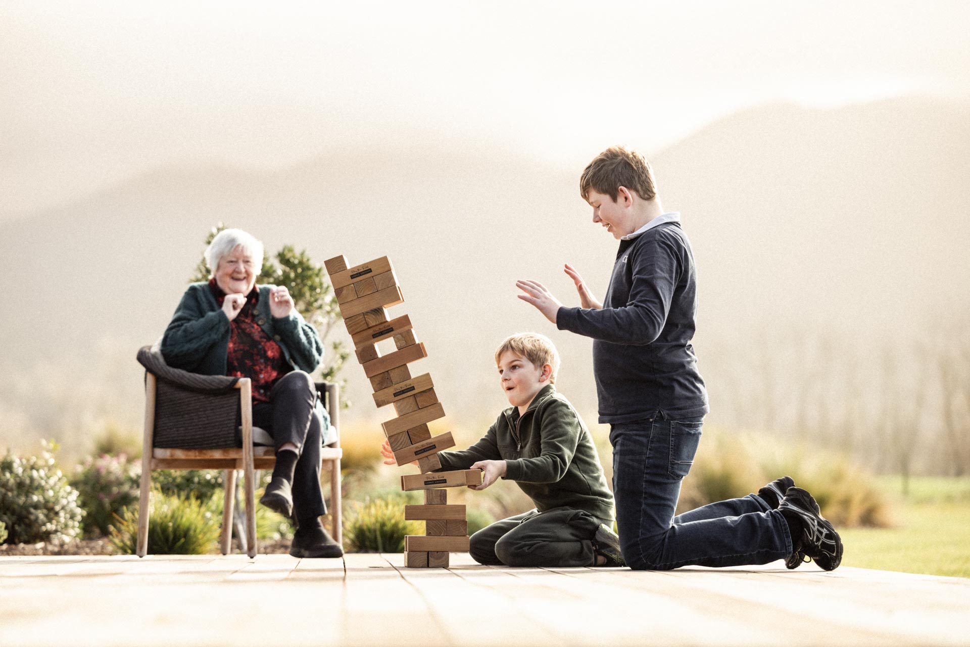 Grandmother watching grandchildren play giant Jenga on the terrace at Whakahā